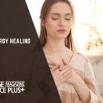 A woman with closed eyes, gently holding her chest in a meditative pose, surrounded by a calm indoor environment.